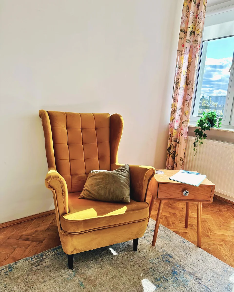 Musztardowy fotel przy oknie w gabinecie przy placu Wilsona.